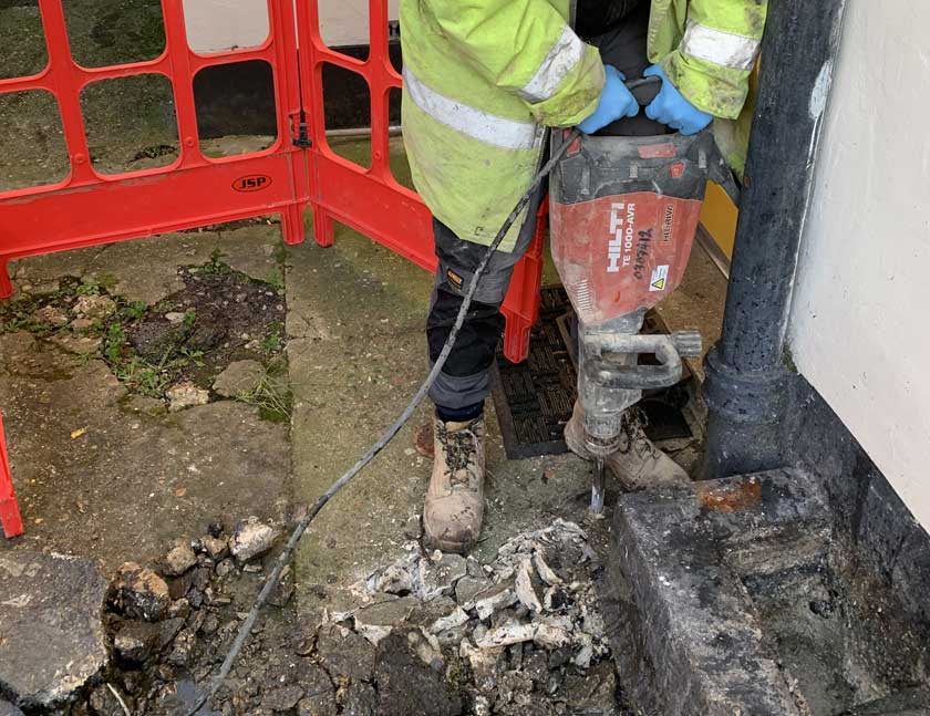 Contractor Breaking Concrete Around Soil Stack