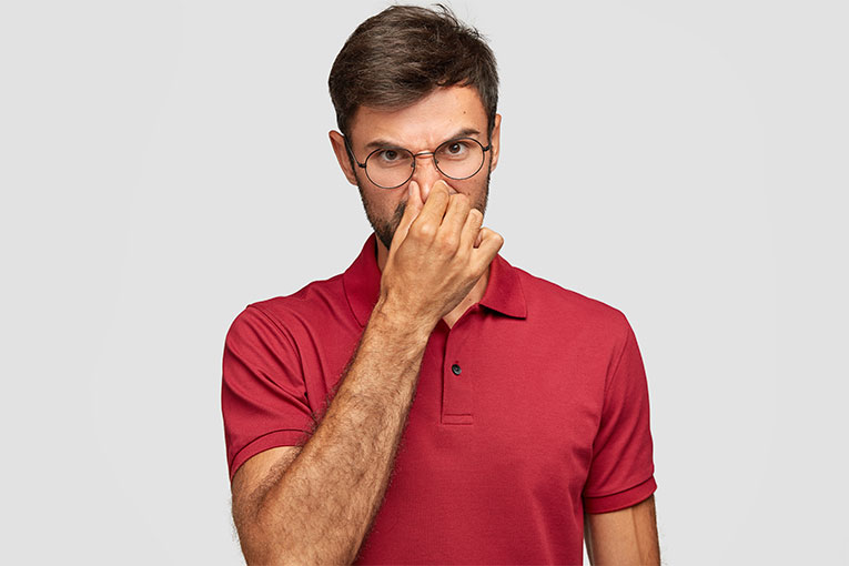A man holding his nose from a bad smell